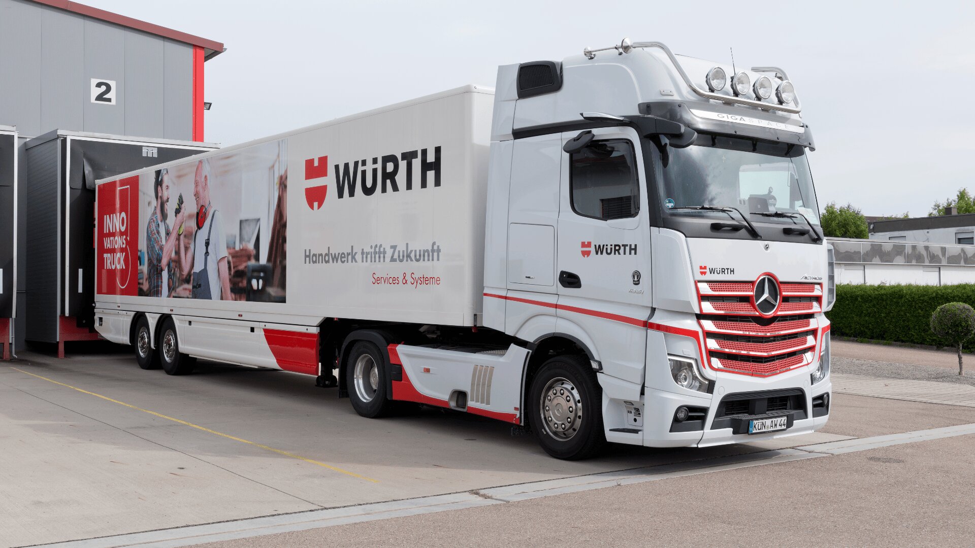 Ein großer weißer Würth-LKW mit roten Akzenten steht an der Laderampe vor einem Lagerhaus. An der Seite des LKWs sind das Würth-Logo und der Slogan „Handwerk trifft Zukunft“ zu sehen.