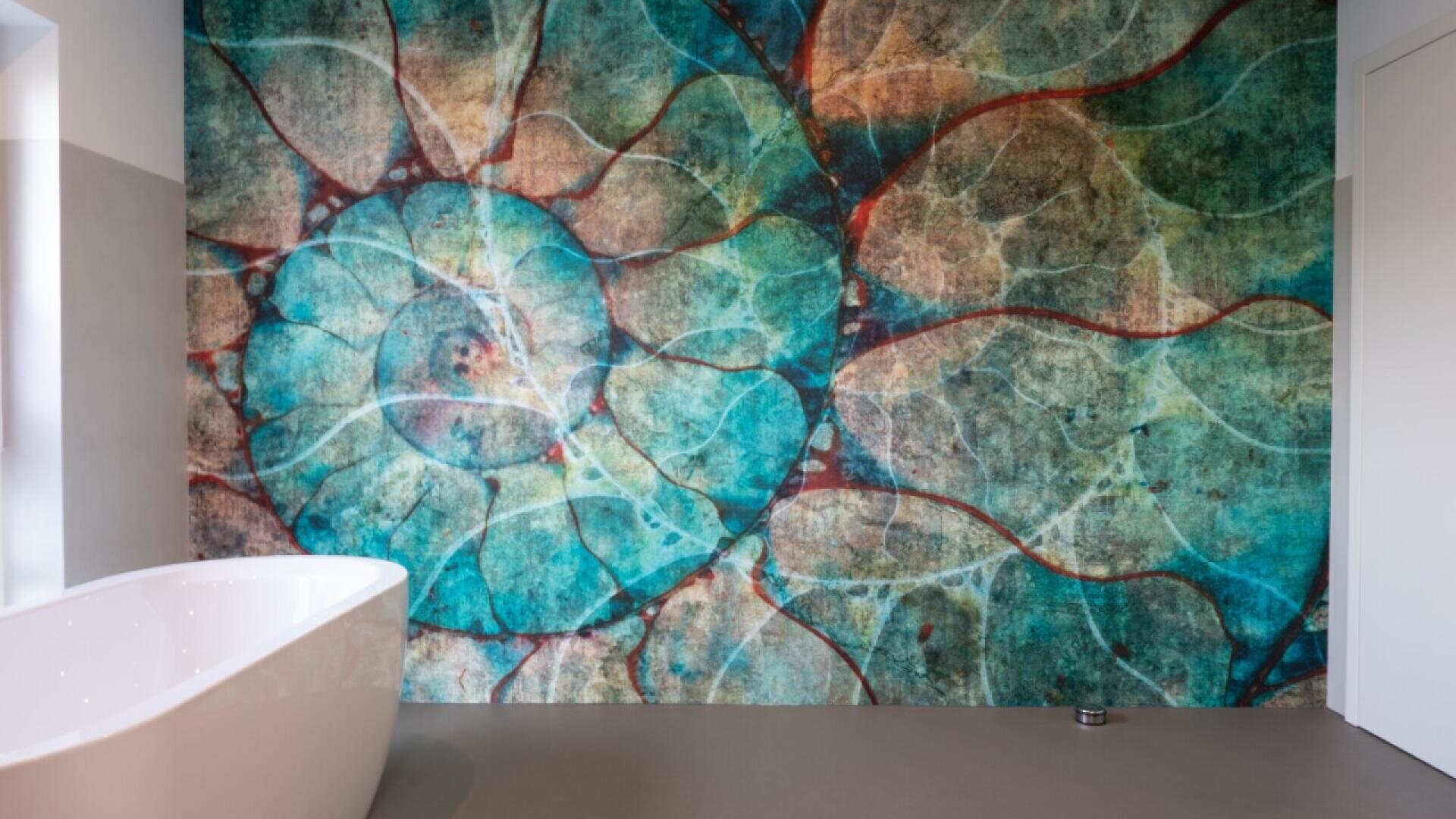 Abstract wall art with circular, vein-like patterns in shades of teal, blue, green, and red behind a modern white bathtub in a minimalist bathroom.