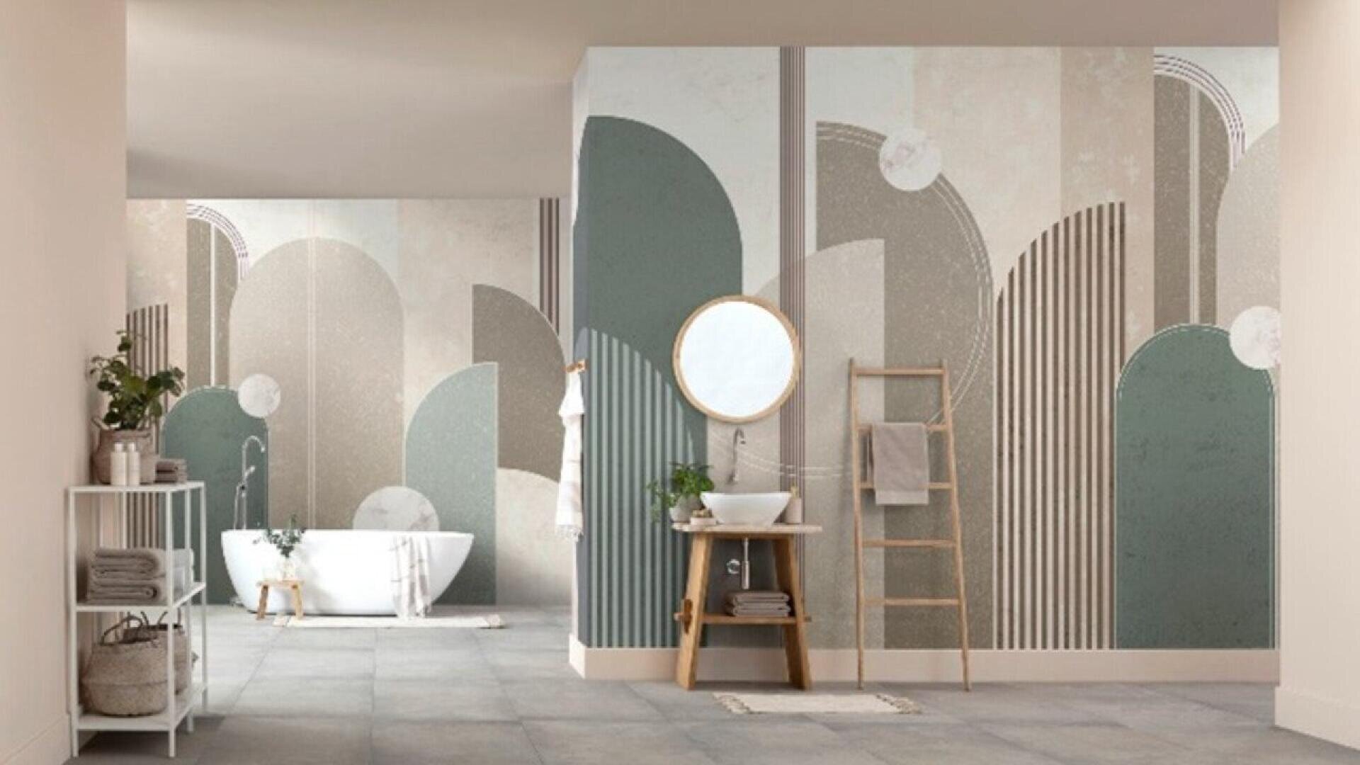 Modern bathroom with geometric-patterned walls in muted greens and taupes, a round mirror above a small wooden sink stand, a ladder towel rack, bathtub, and minimalistic decor with plants.