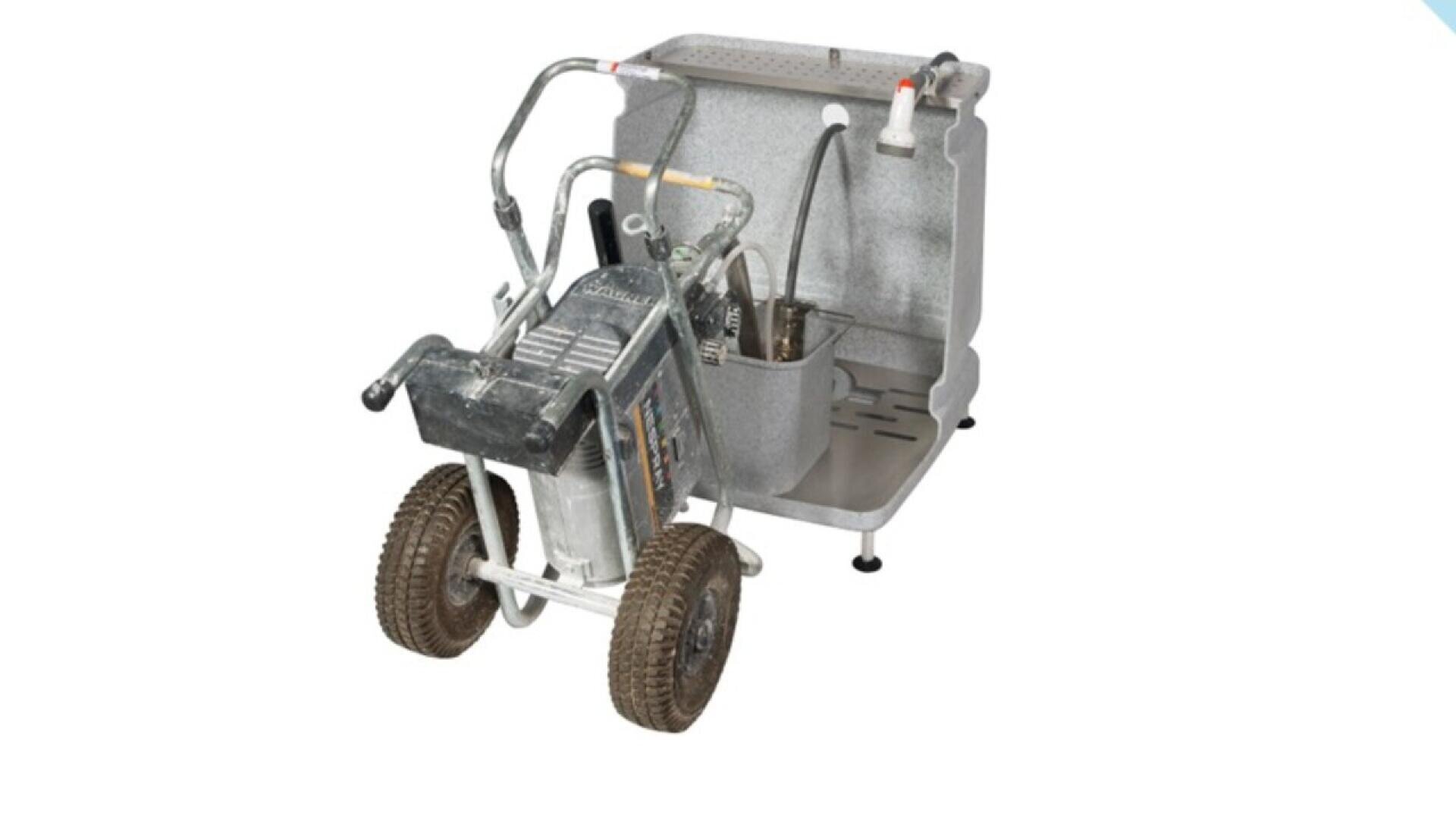 A portable paint sprayer cleaning station with a gray base, two wheels, metal handles, and attached hoses, designed for cleaning painting equipment. The station is set against a plain white background.