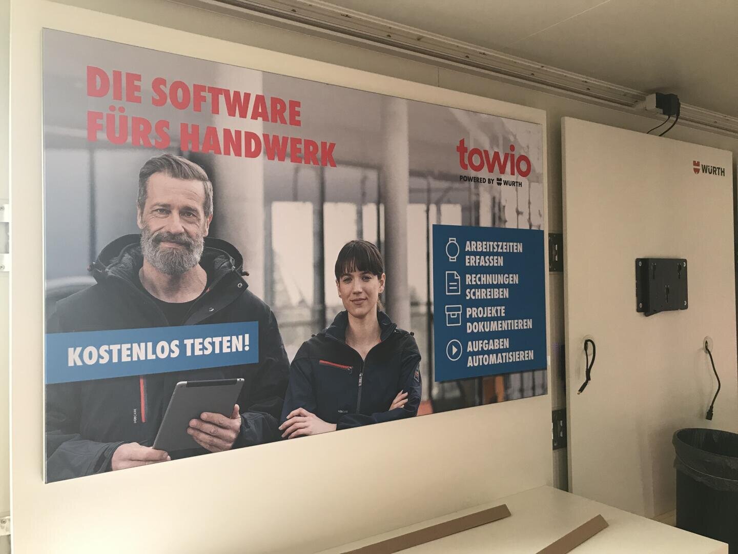 Eine deutsche Werbung für die Towio-Software zeigt einen lächelnden Mann mit einem Tablet und eine Frau neben ihm. Der Text wirbt für kostenlose Testversionen der Software und nennt ihre Funktionen für geschäftliche Aufgaben.