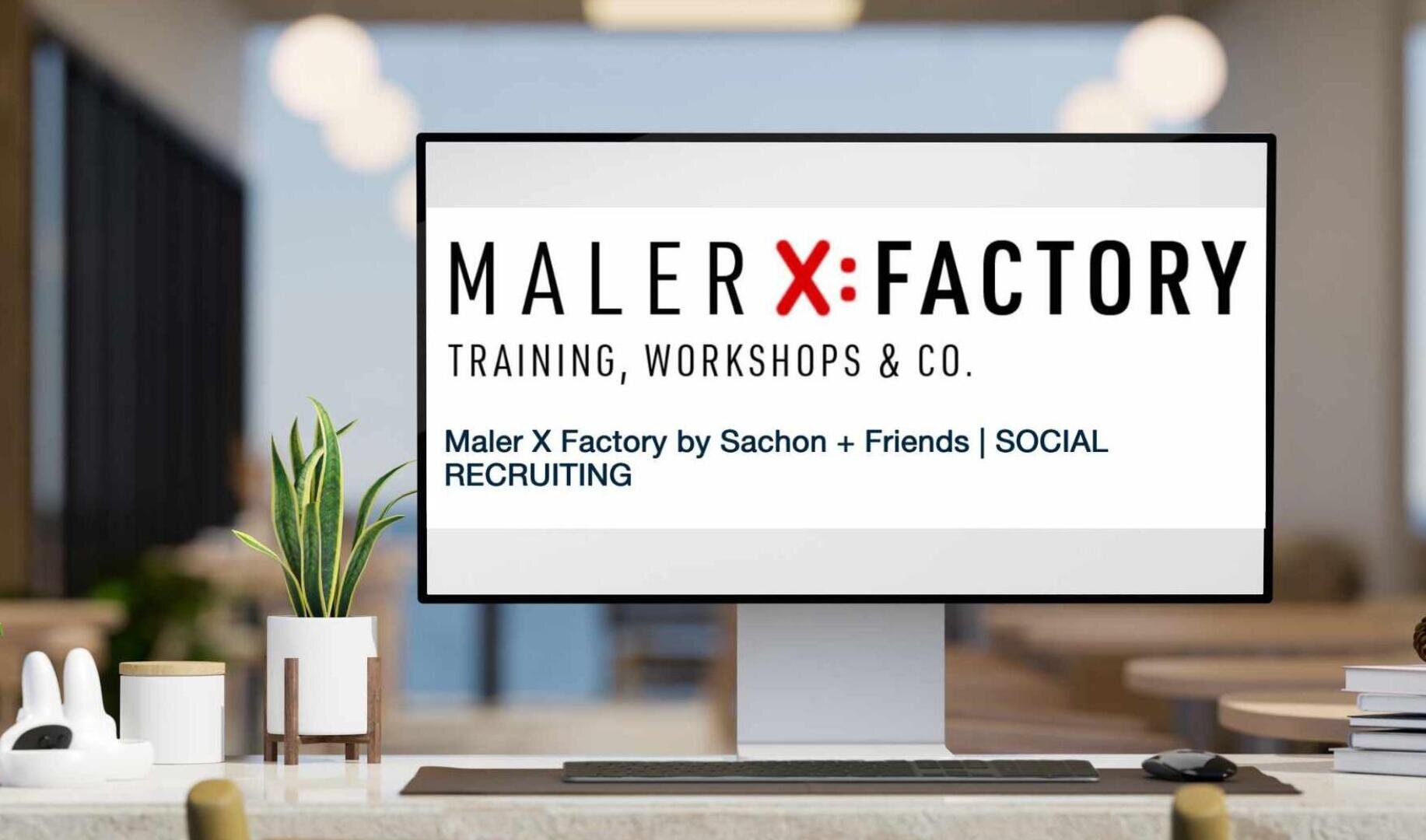 Ein Computermonitor auf einem modernen Bürotisch zeigt das Logo der Maler X Factory sowie Texte zu Schulungen, Workshops und Social Recruiting von Sachon + Friends. Im Hintergrund ist ein unscharfer, offener Büroraum zu sehen.
