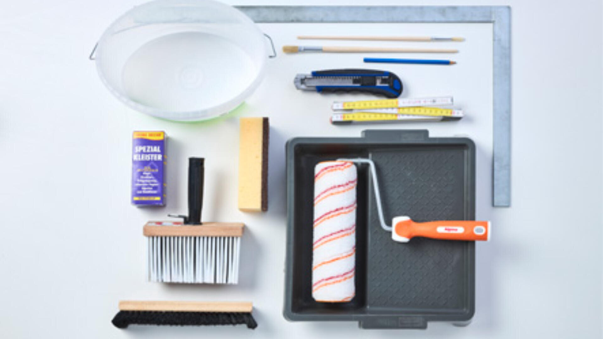 Eine Sammlung von Maler- und Tapezierwerkzeugen, darunter eine Farbrolle, ein Tablett, Pinsel, Schwämme, ein Maßband, ein Teppichmesser, Bleistifte, ein Metallwinkel, Kleister und ein Wassereimer, ordentlich auf einer weißen Oberfläche angeordnet.