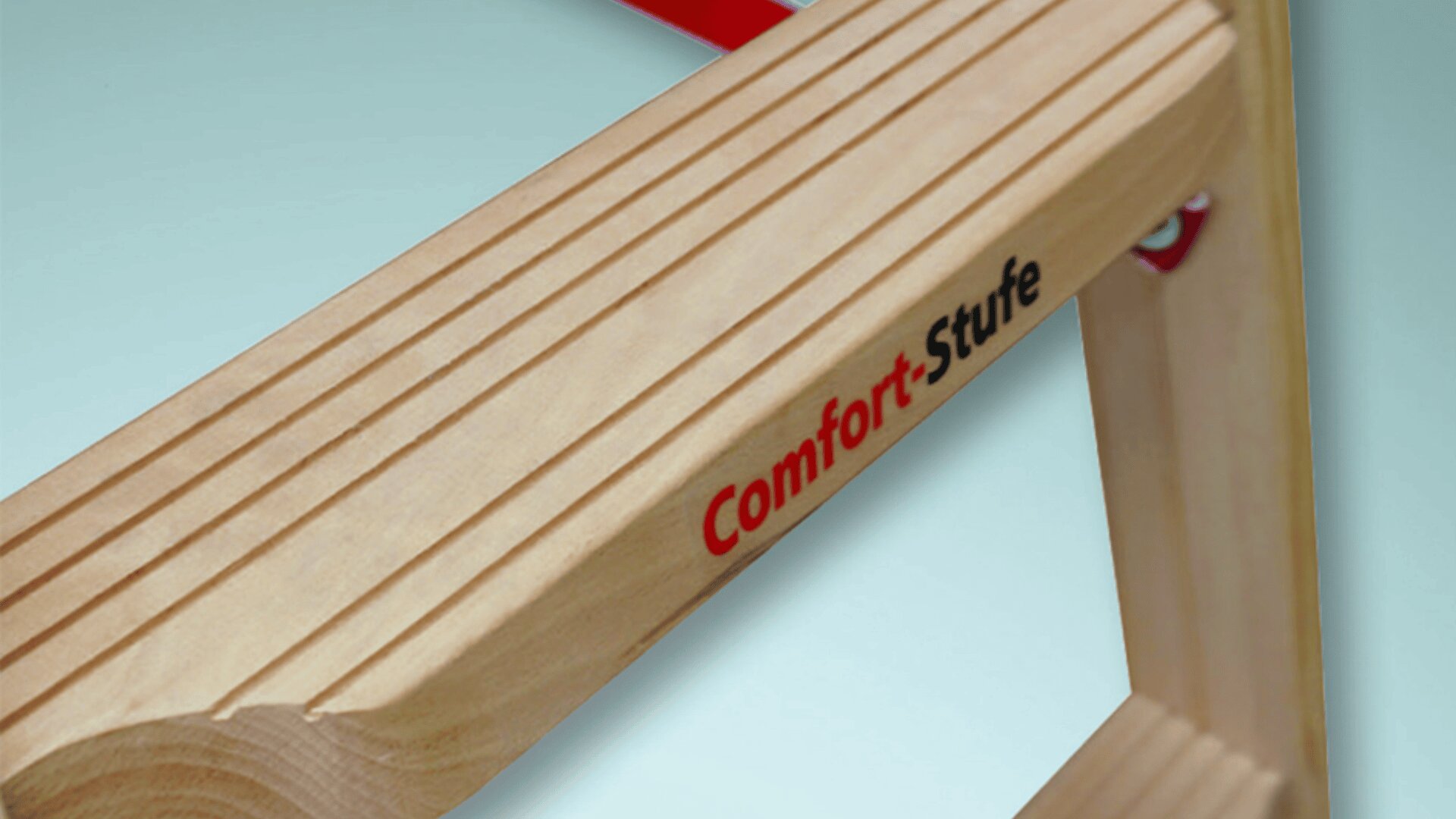 Nahaufnahme einer hölzernen Leitersprosse mit Rillen zum Greifen und dem seitlichen Aufdruck „Comfort-Stufe“ in Rot und Schwarz.